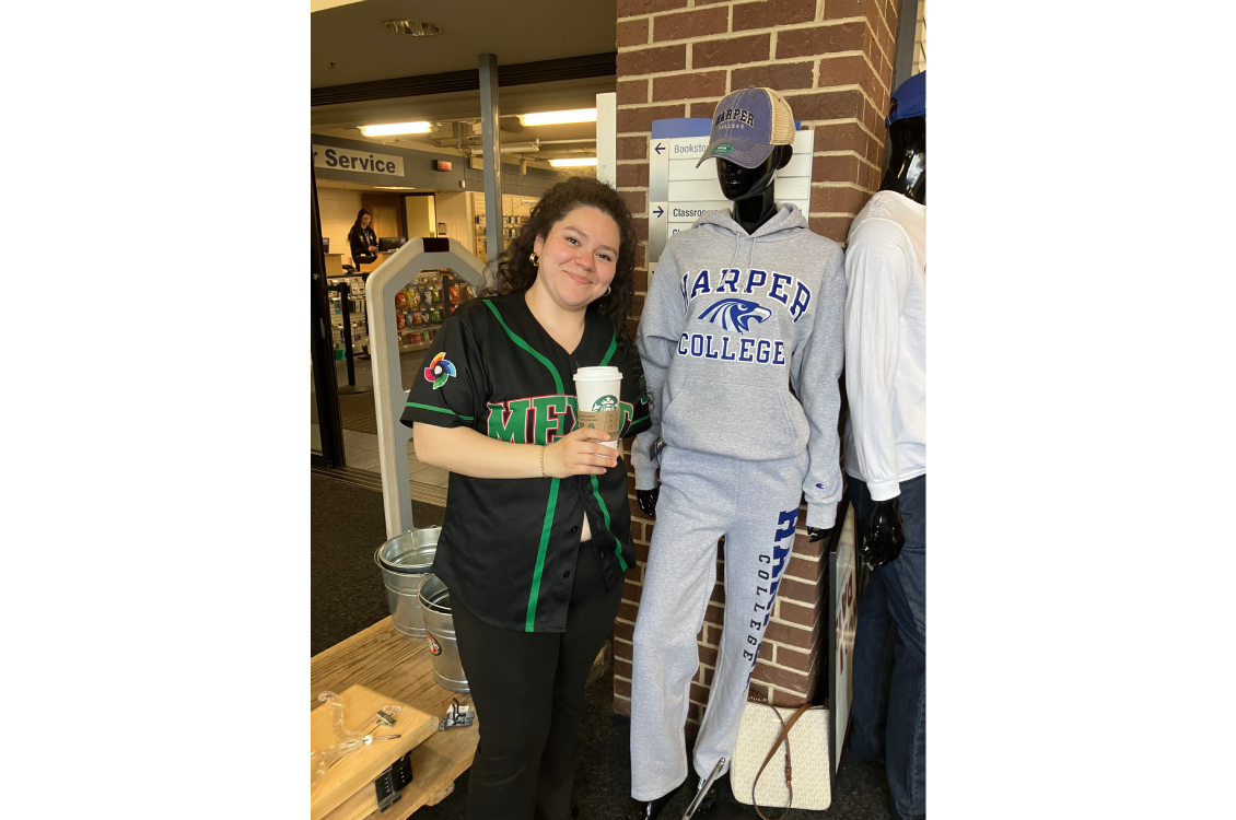 A student posing with a mannequin wearing Harper merchandise