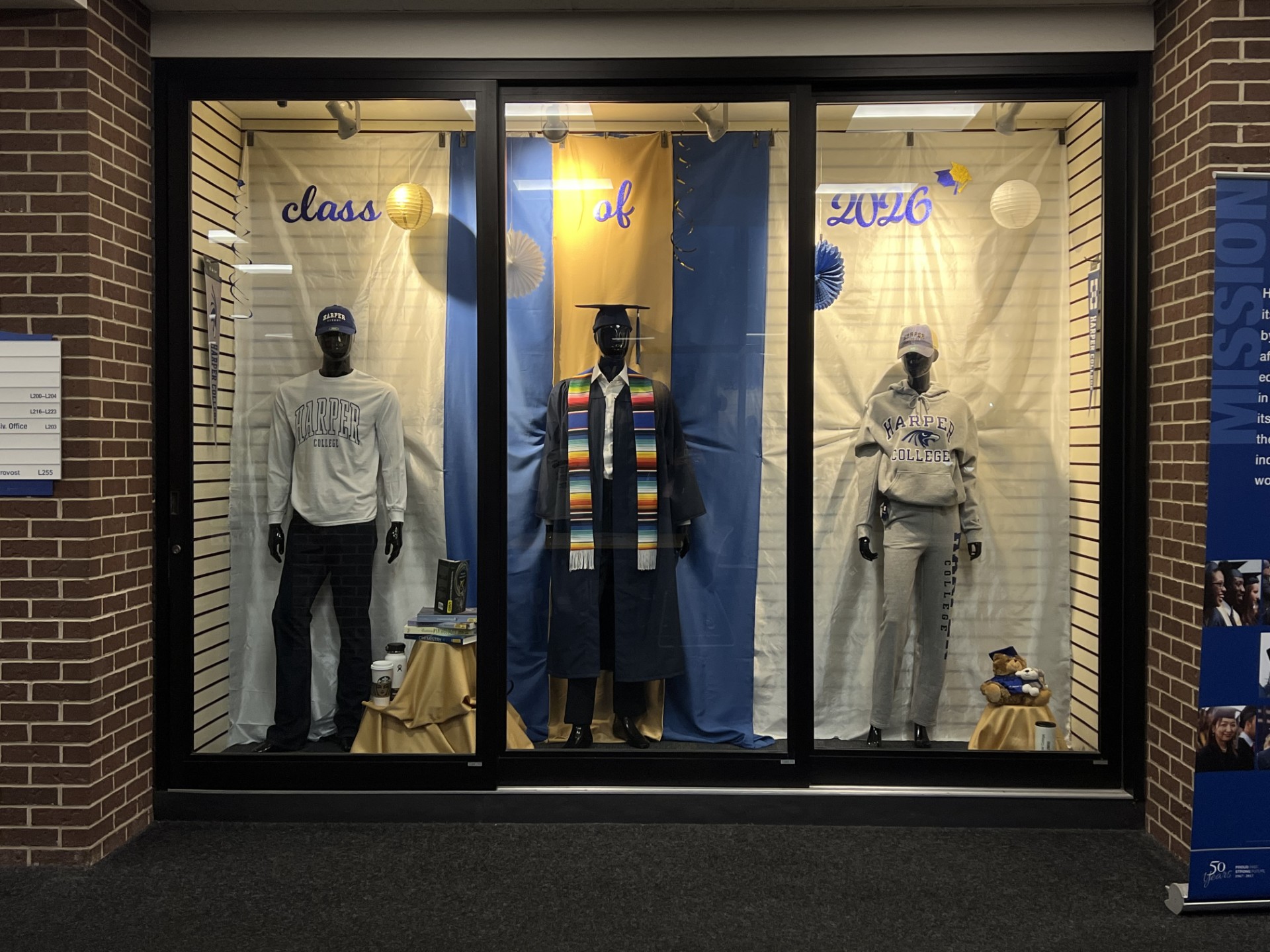 the Harper Bookstore display featuring two mannequins in Harper gear and one in graduation regalia