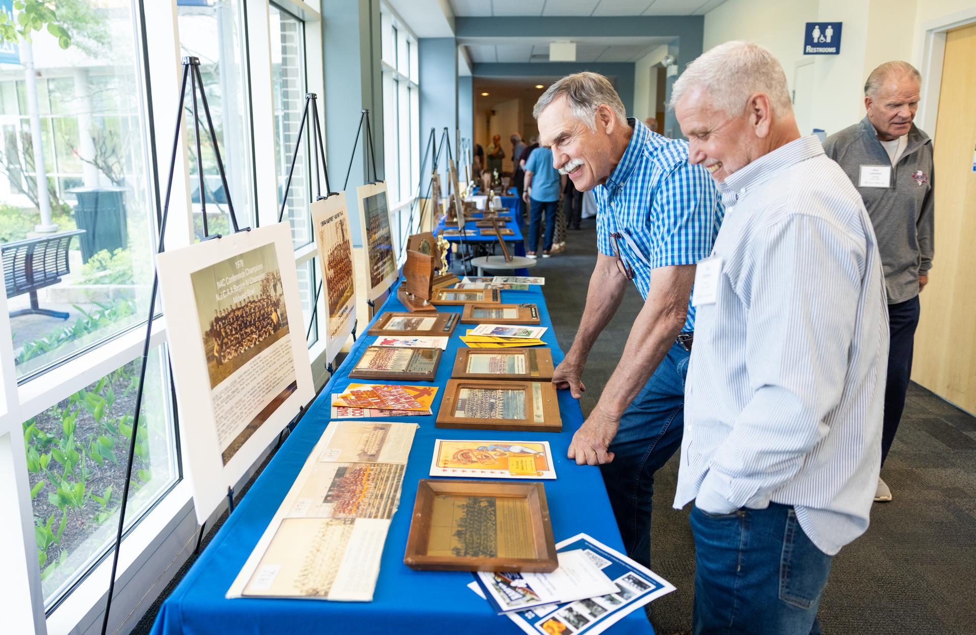 Harper College Football alumni examining vintage football memorabilia from the Harper College Archives