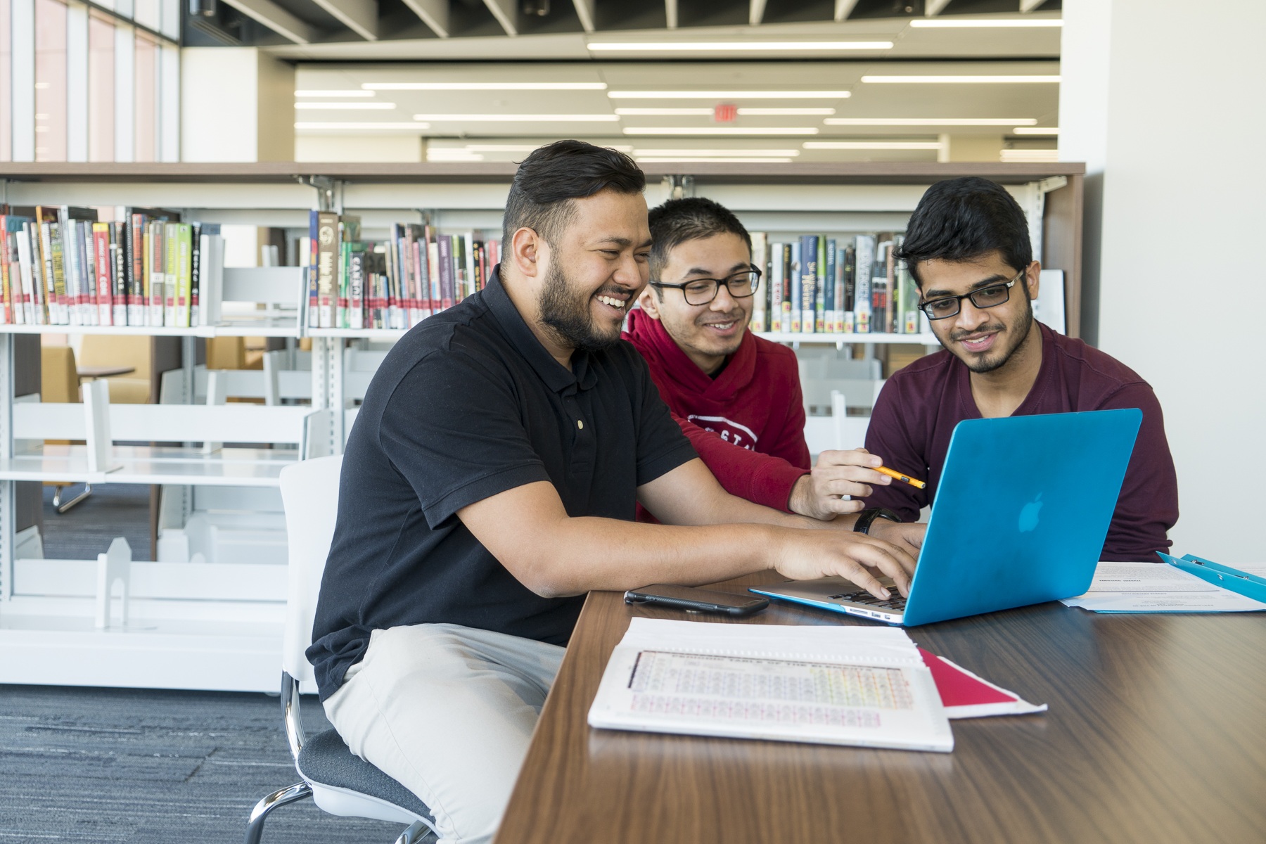 AI degree Three students work on a laptop computer