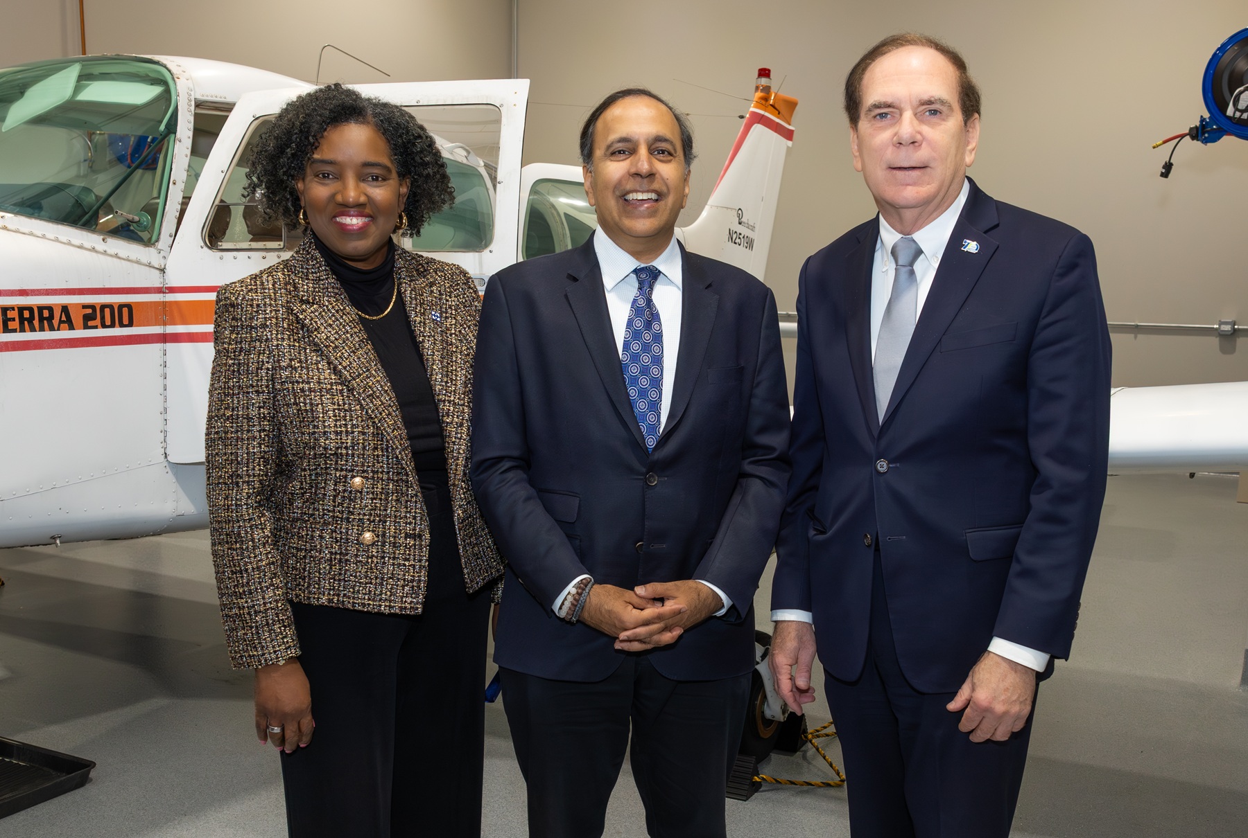 Harper College President Dr. Avis Proctor, Rep. Raja Krishnamoorthi and Schaumburg Village President Tom Dailly stand in front of an airplane during the ribbon-cutting ceremony for Harper's Aviation Maintenance Lab.