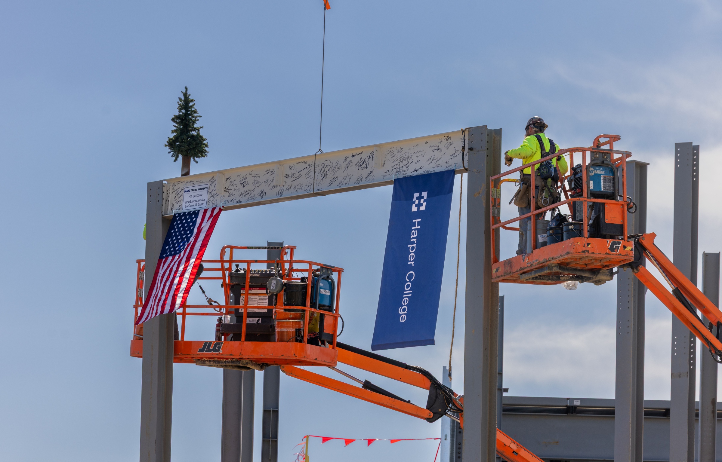 A member of the construction crew helps put the signed beam into place