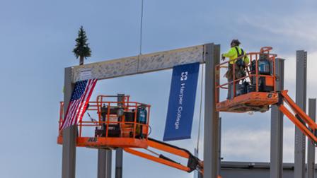 A member of the construction crew places the signed beam into place