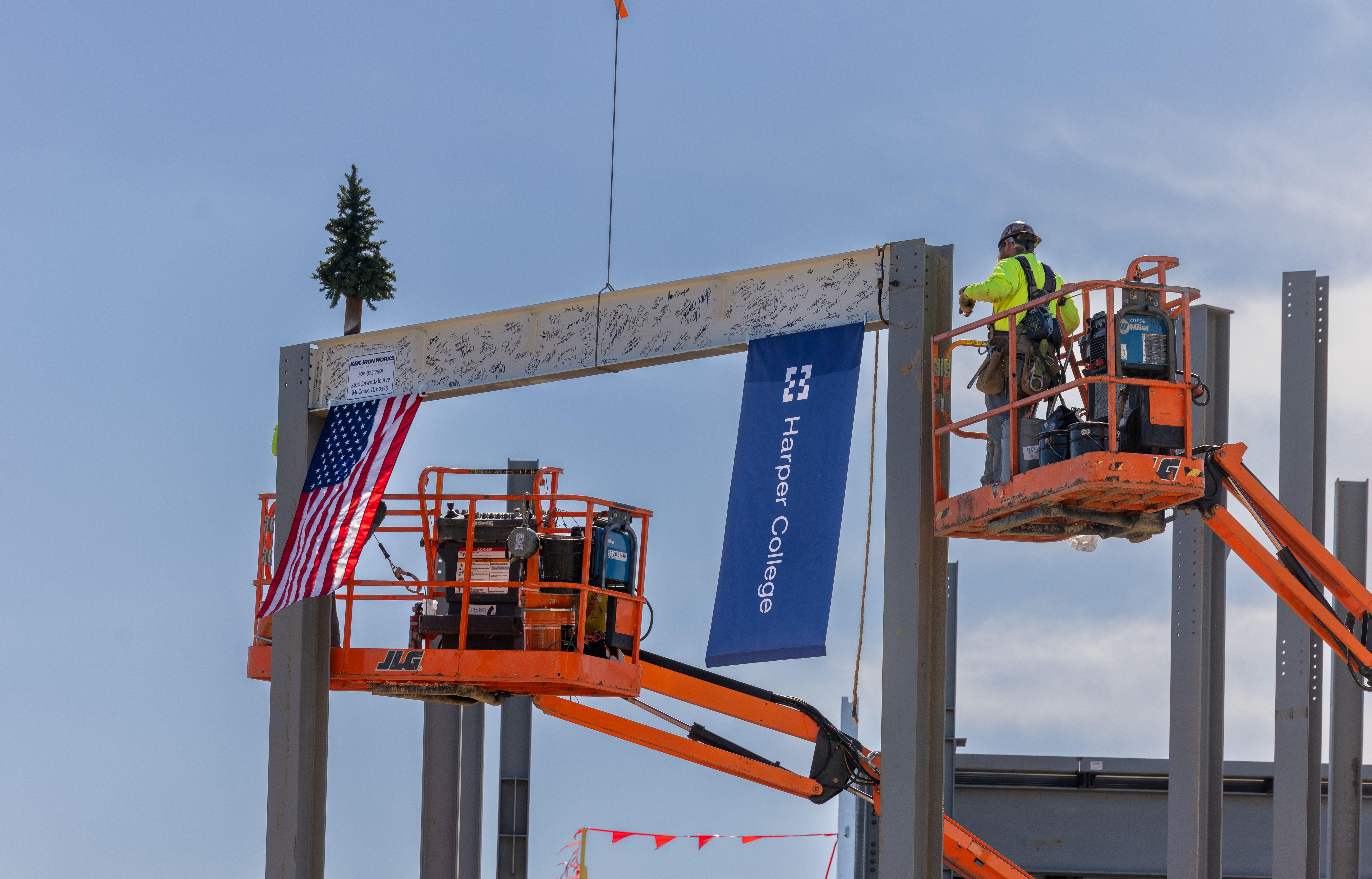 A member of the construction crew helps put the signed beam into place