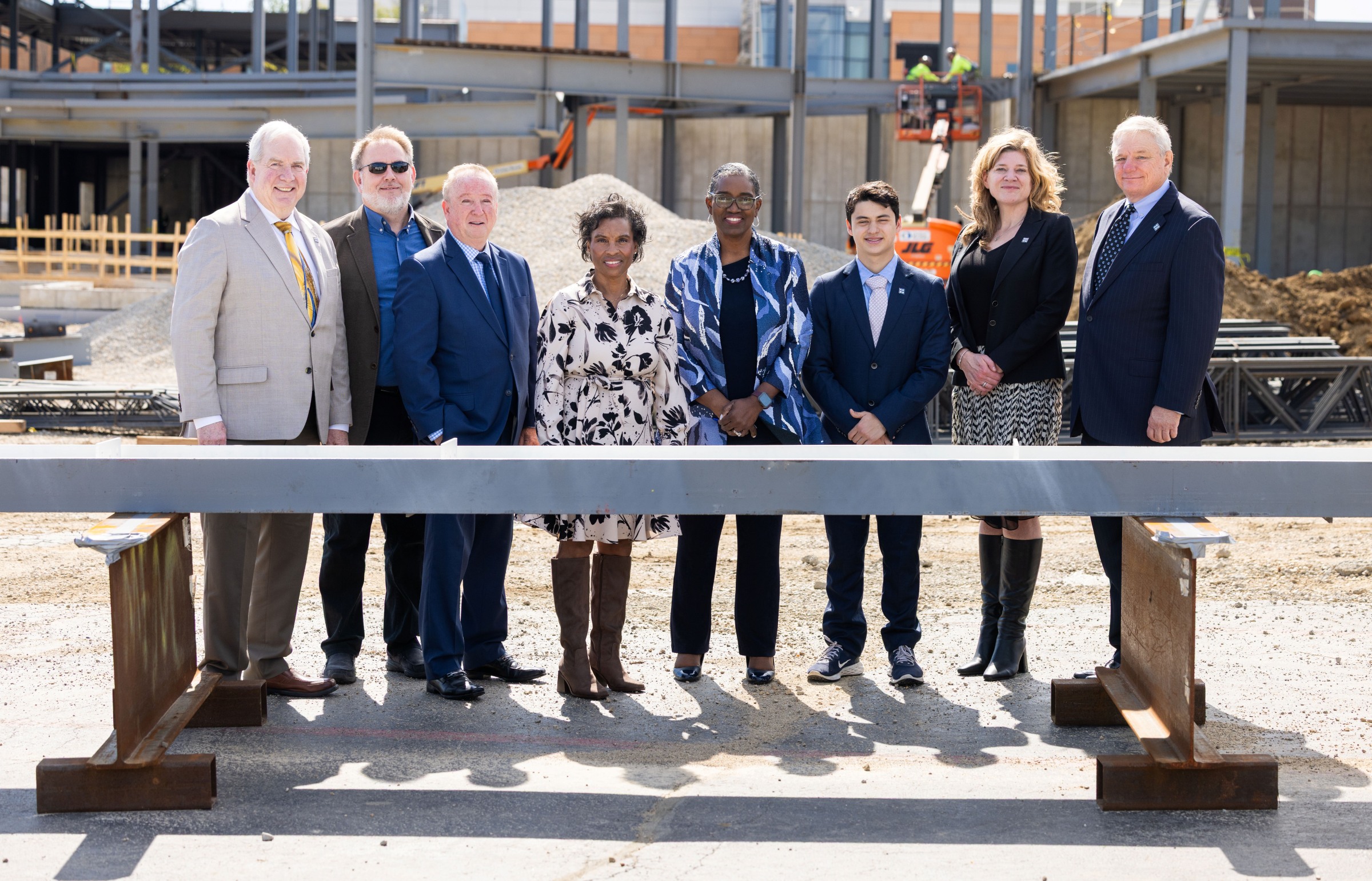 Harper College leaders stand beside the signed beam at the beam-signing ceremony