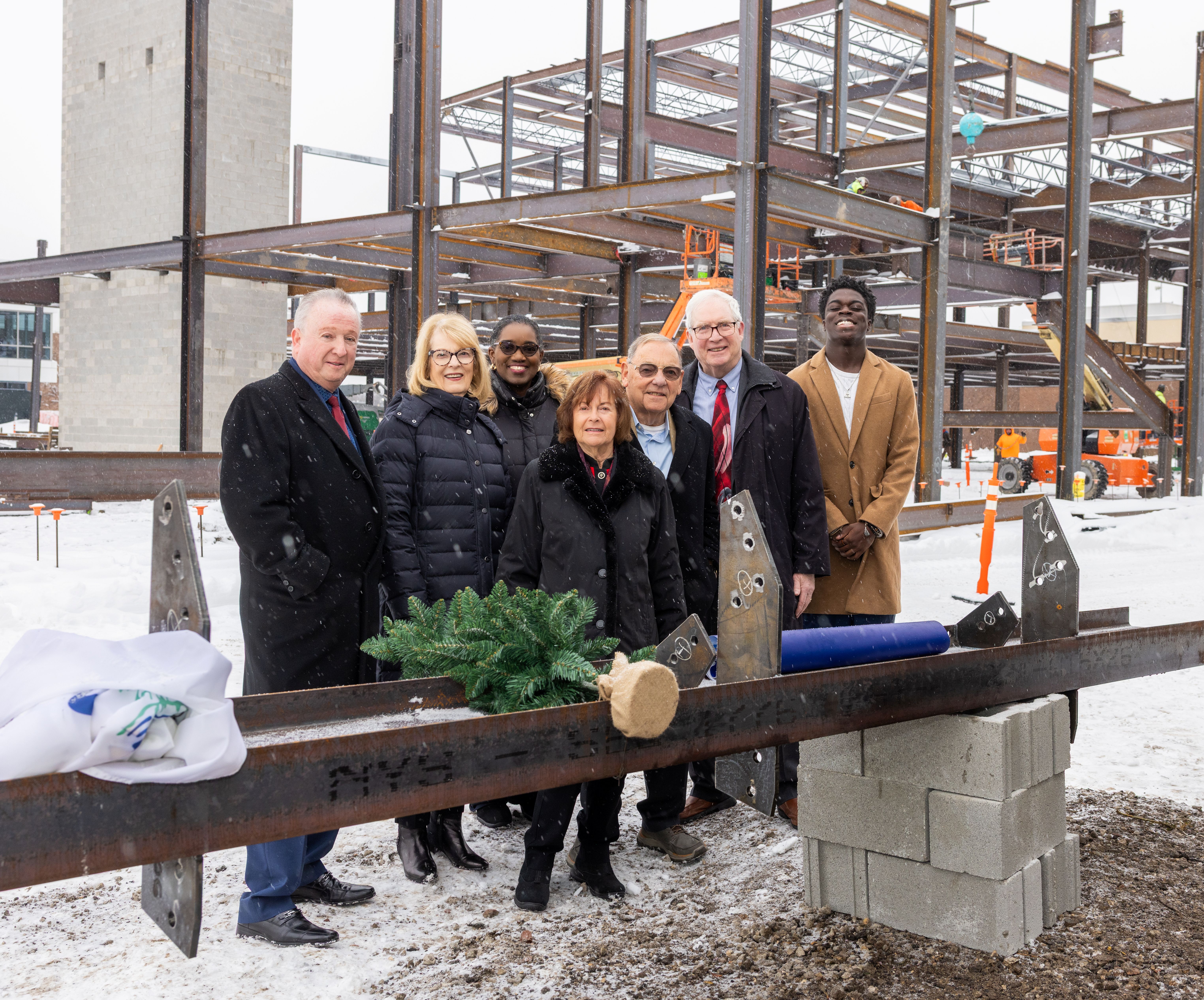 Harper College trustees, Dr. Avis Proctor and Rita and John Canning pose behind a structural beam at the Canning Student Center and University Center beam-signing ceremony.