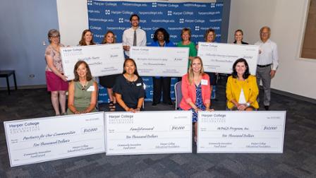 Grant recipients pose with oversized checks.