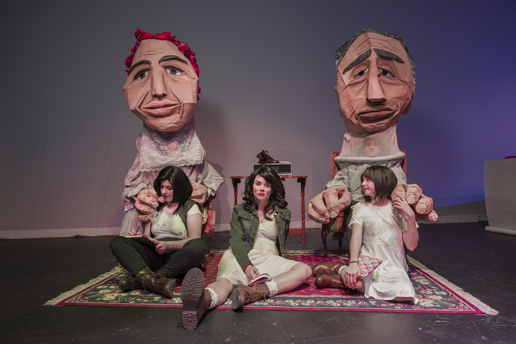 Five actors from 'Dirty Turk aka Dirty Immigrant' are pictured. Three actors play the main character Ozlem at different ages and others wear large costumes as her grandparents.