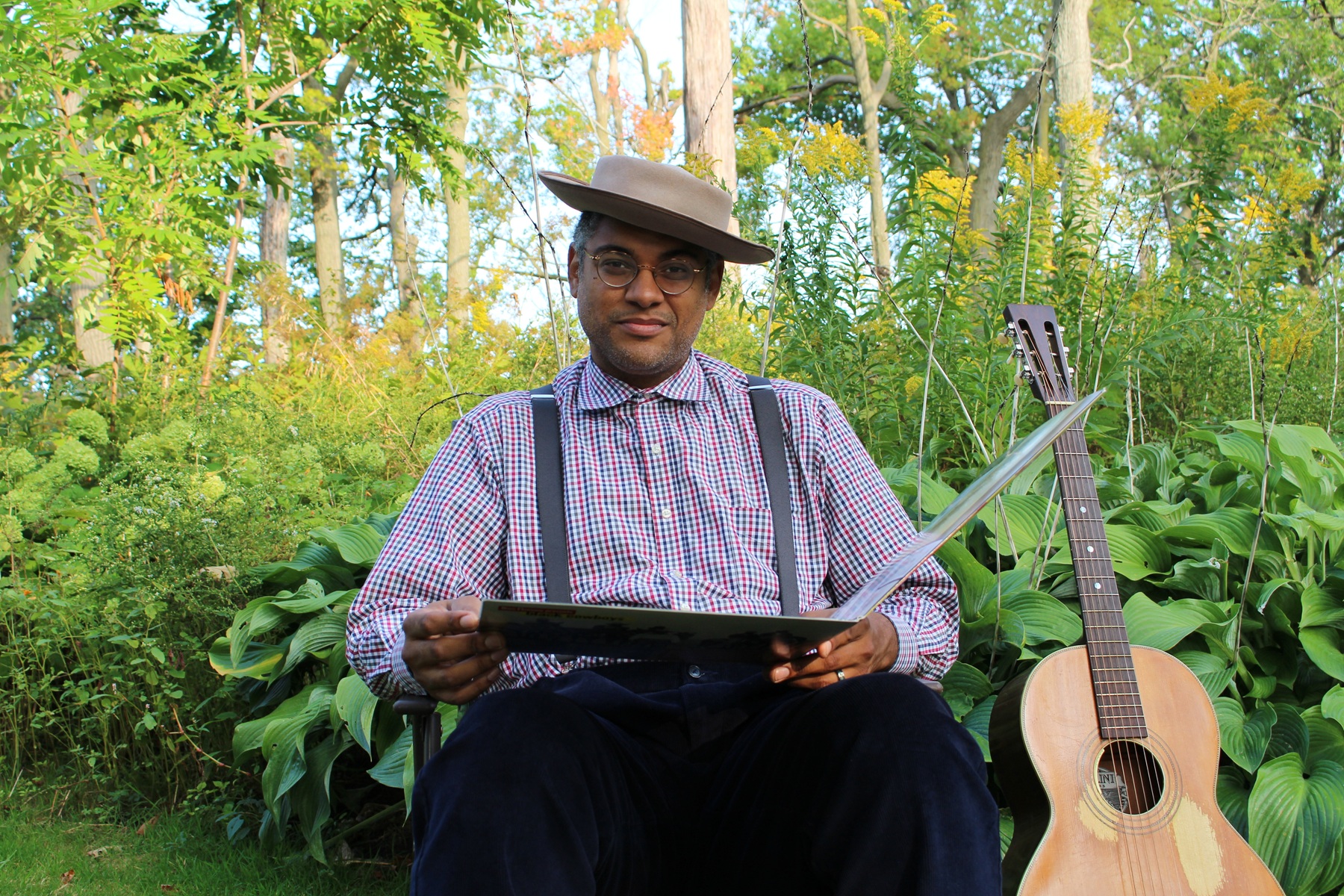 Dom Flemons by Nate Kinard Jr. Dom Flemons sits surrounded by instruments and trees