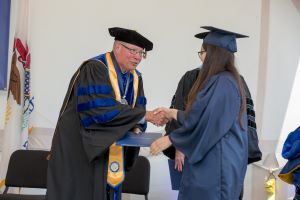 Dr. Ender shakes the hand of a Harper College graduate