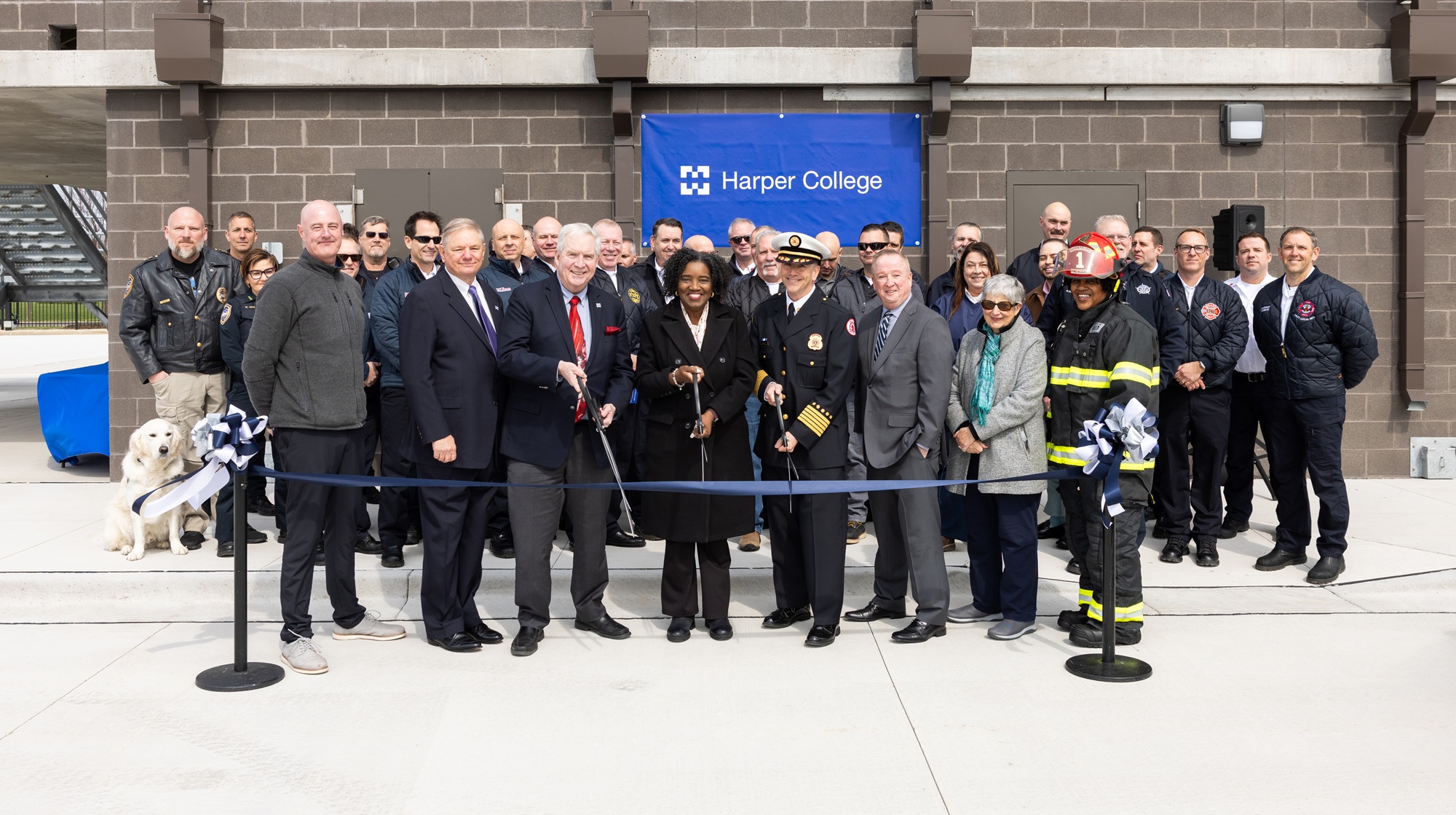 Harper College President Dr. Avis Proctor, members of the Harper Board of Trustees, faculty and area first responders pose in front of the new Emergency Services Training Center and cut a ribbon