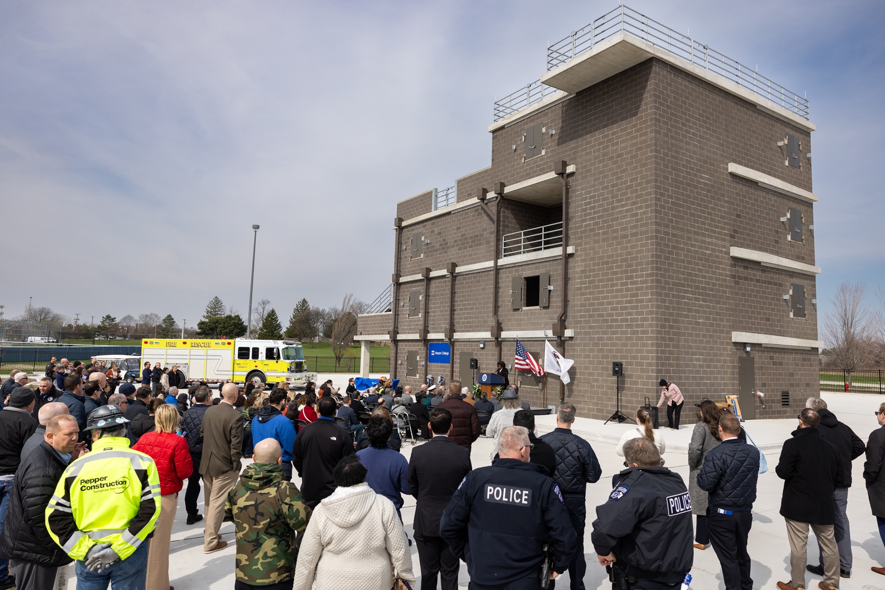 A crowd stand in front of Harper College's Emergency Services Training Center.