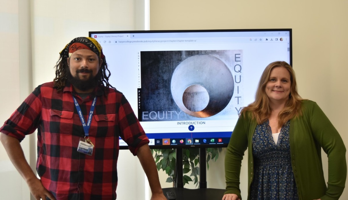 Andre Berchiolly and Stephanie Whalen stand in front of an image created by Martinez E-B Garcias for the Equity Literacy Project.