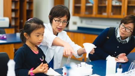 Dr. Tong Cheng demonstrates a science experience to a young student