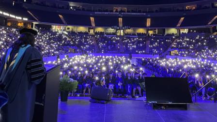 Harper College graduates, friends and family hold up their cell phone flashlights at Commencement