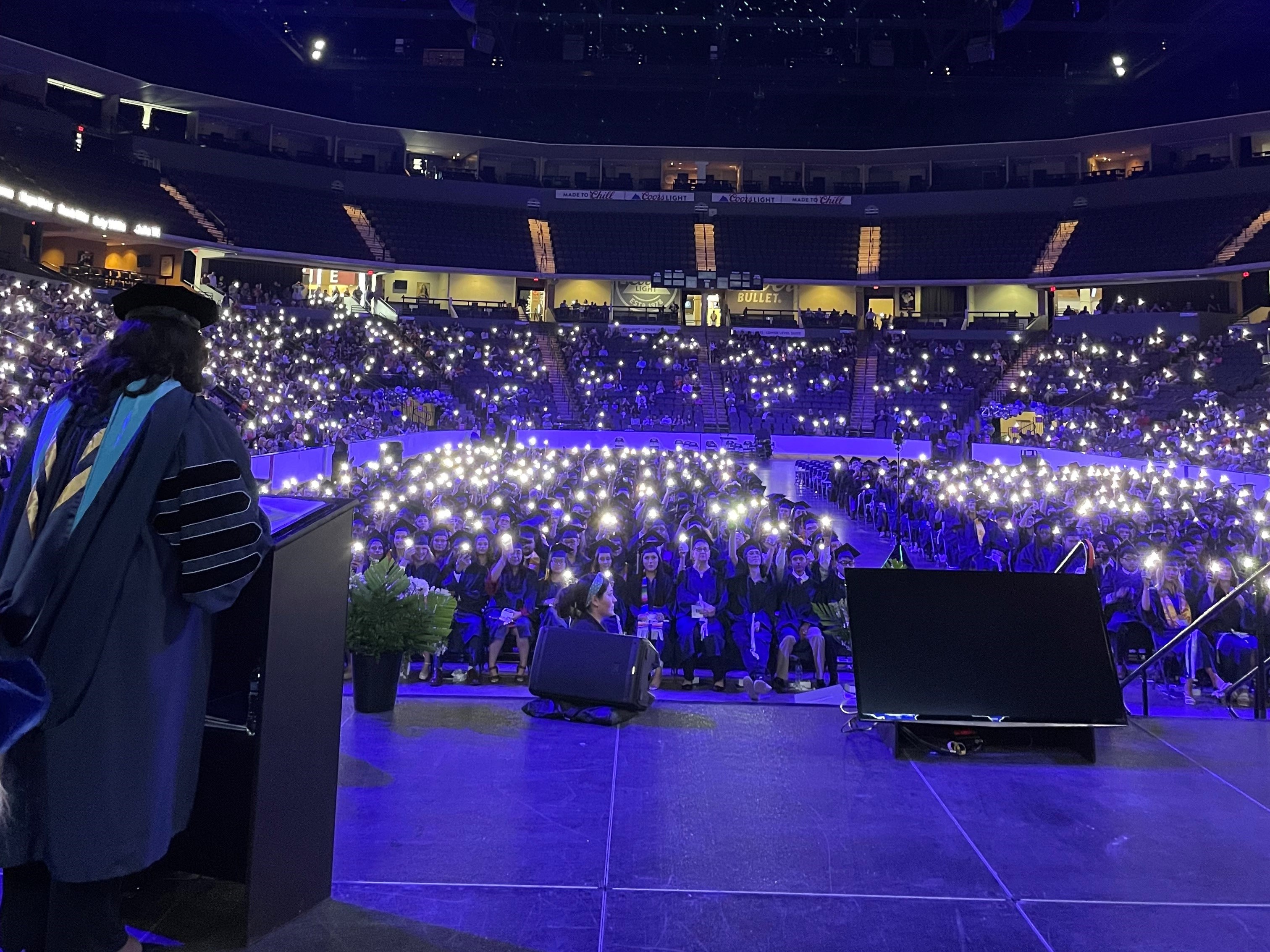 Graduates hold up their cell phone flashlights