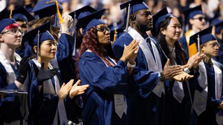 Several Harper College graduates applaud at the Commencement ceremony