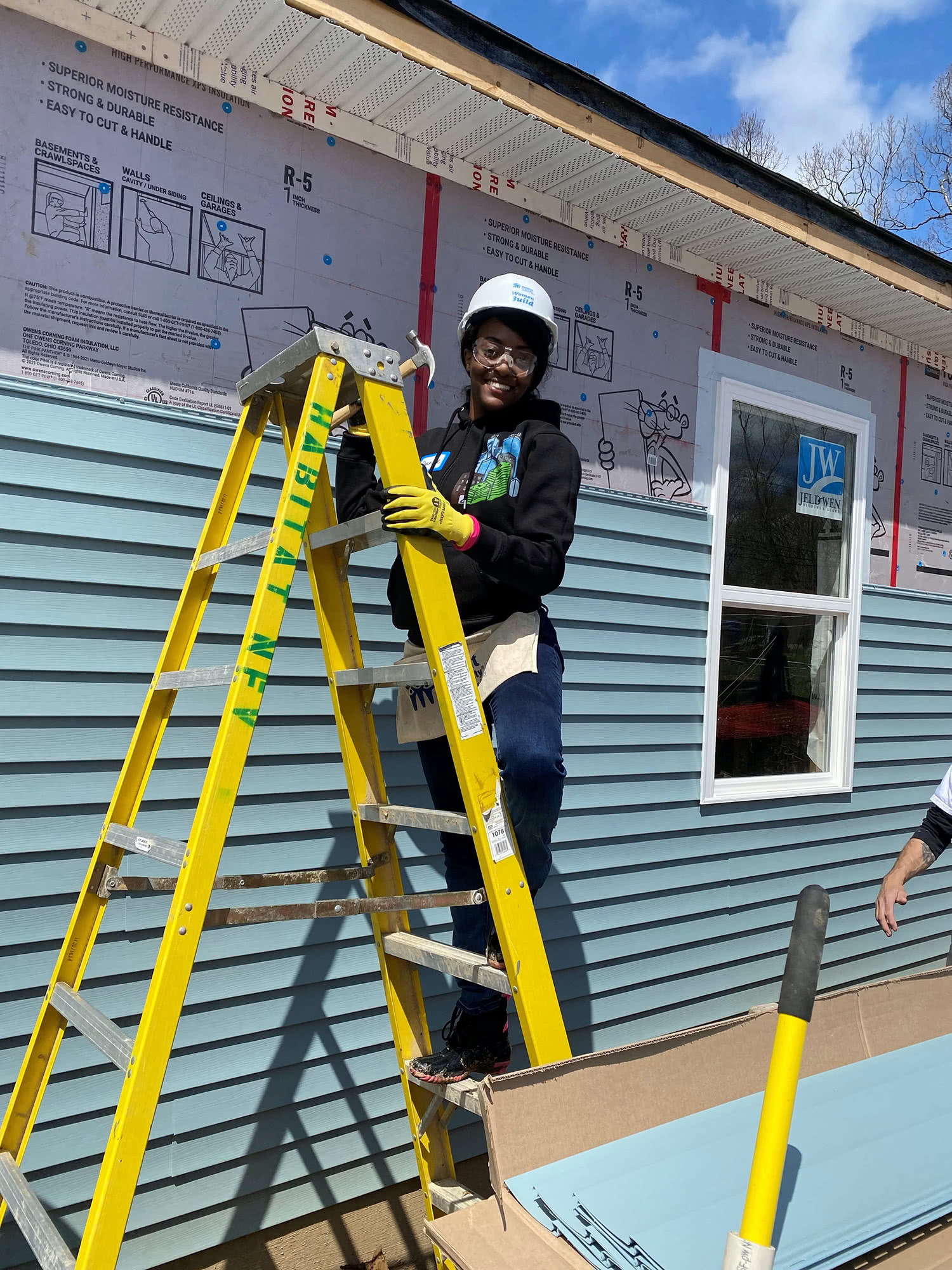 Shauntae Gore on a ladder installing siding