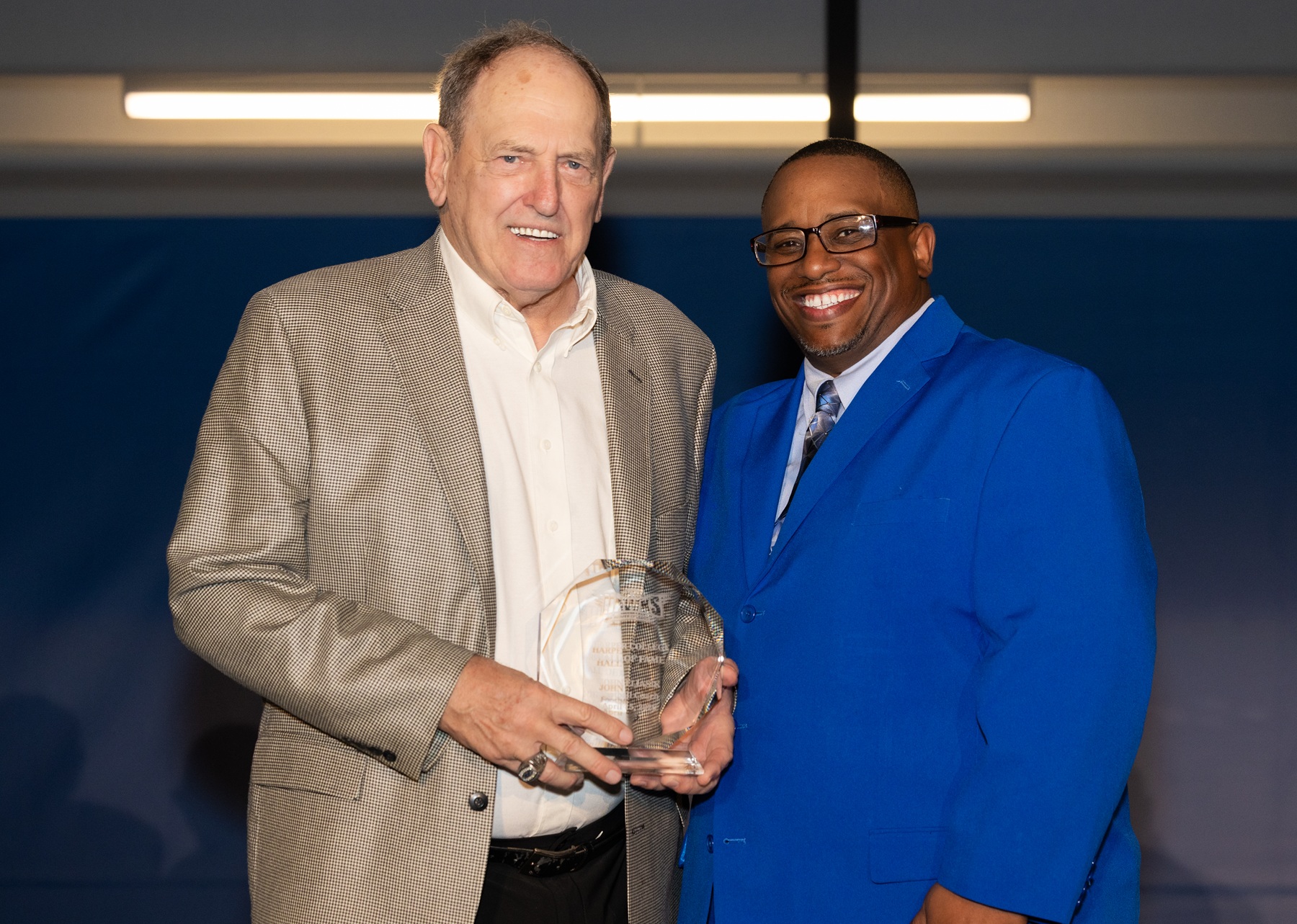 John Eliasik holds his Hall of Fame award and stands with Dr. Cedric Brown
