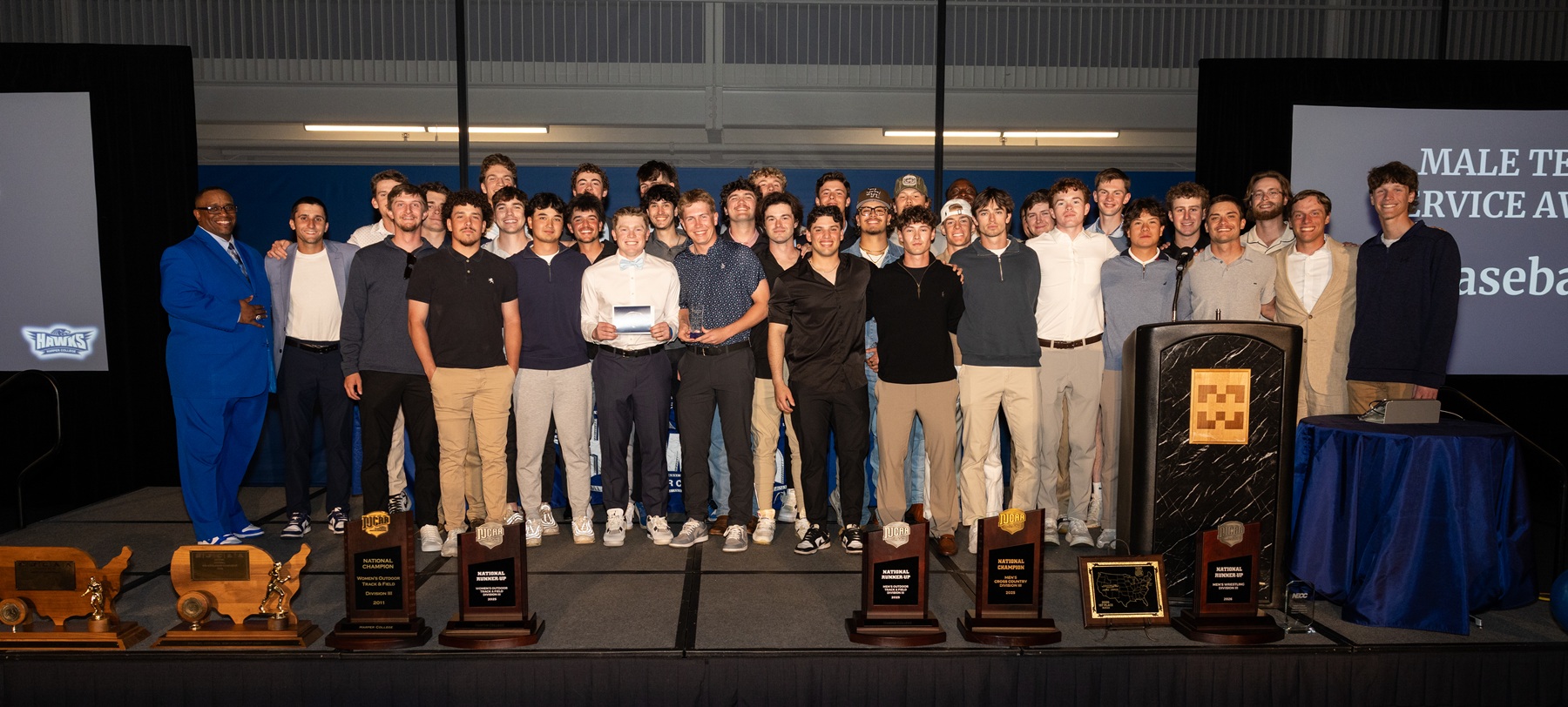 Members and coaches from Harper's Men's Baseball Team stand on a stage after earning the Male Team Service Award.