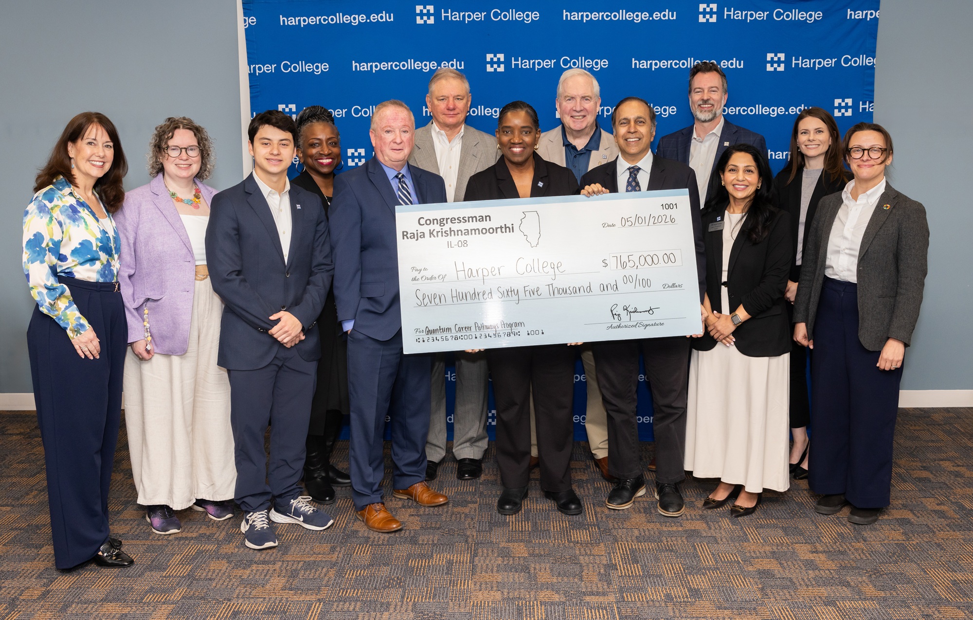U.S. Rep. Raja Krishnamoorthi stands with Dr. Avis Proctor, other Harper leaders and a large check for $765,000 to symbolize the funding he helped deliver to Harper's quantum science programs