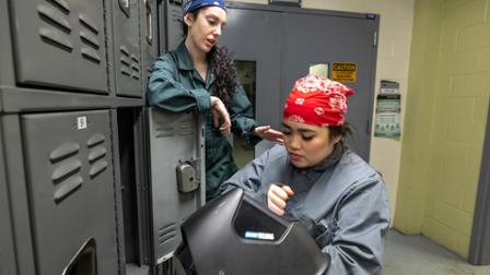 Two characters in Lettie talk by a locker