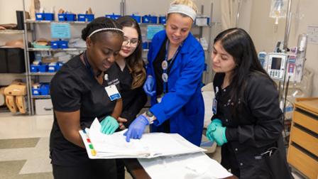A group of nursing students gather around a patient's chart