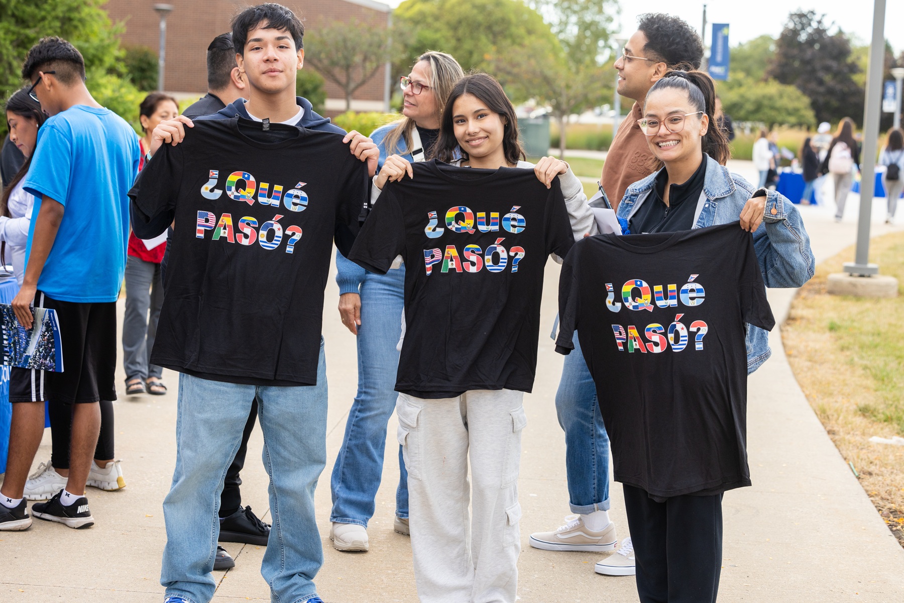 Student hold up Que PASO? shirts at Harper Fiesta
