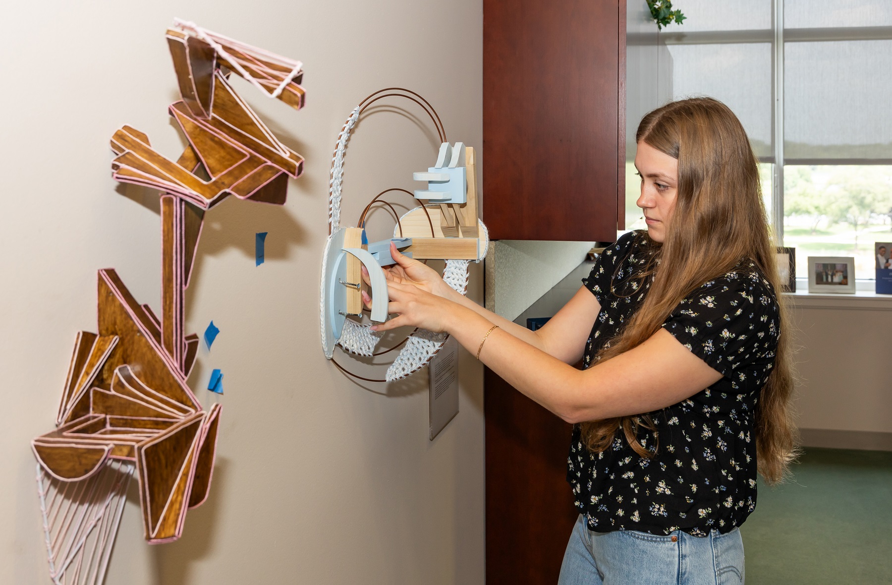 Harper College student Caitlin Baier installs her sculpture, chosen for the 2023 President's Art Selection Award, outside of Dr. Avis Proctor's office.