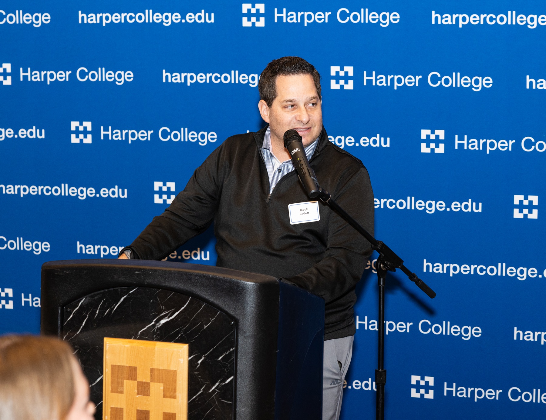 Harper alumnus Jake Sadoff speaks behind a podium