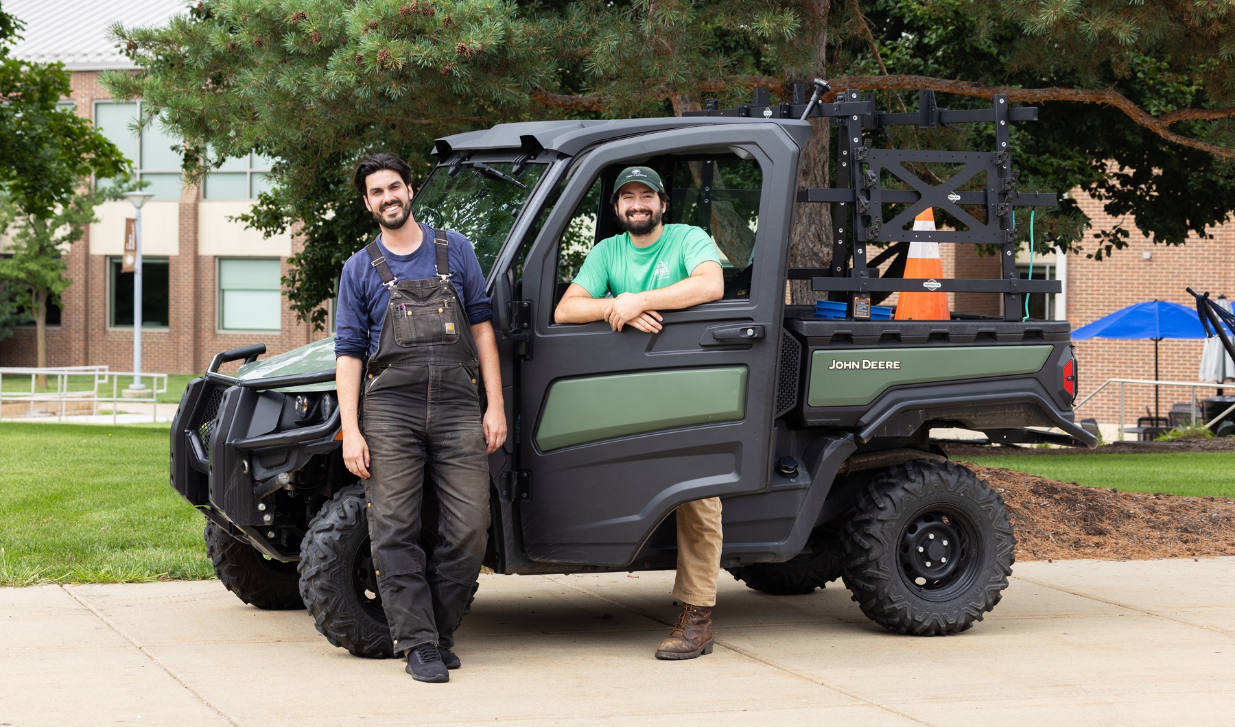 Billy Maloney and Jackson Zinck stand with a Roads and Grounds vehicle on Harper College's campus
