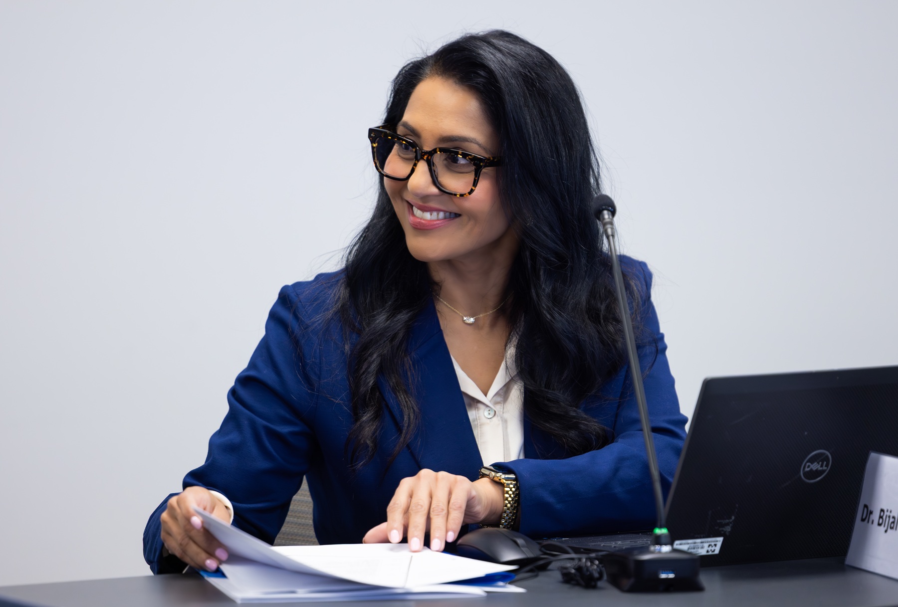 Harper College Trustee Bijal Chaturvedi sits at a table, smiling, during a board workshop