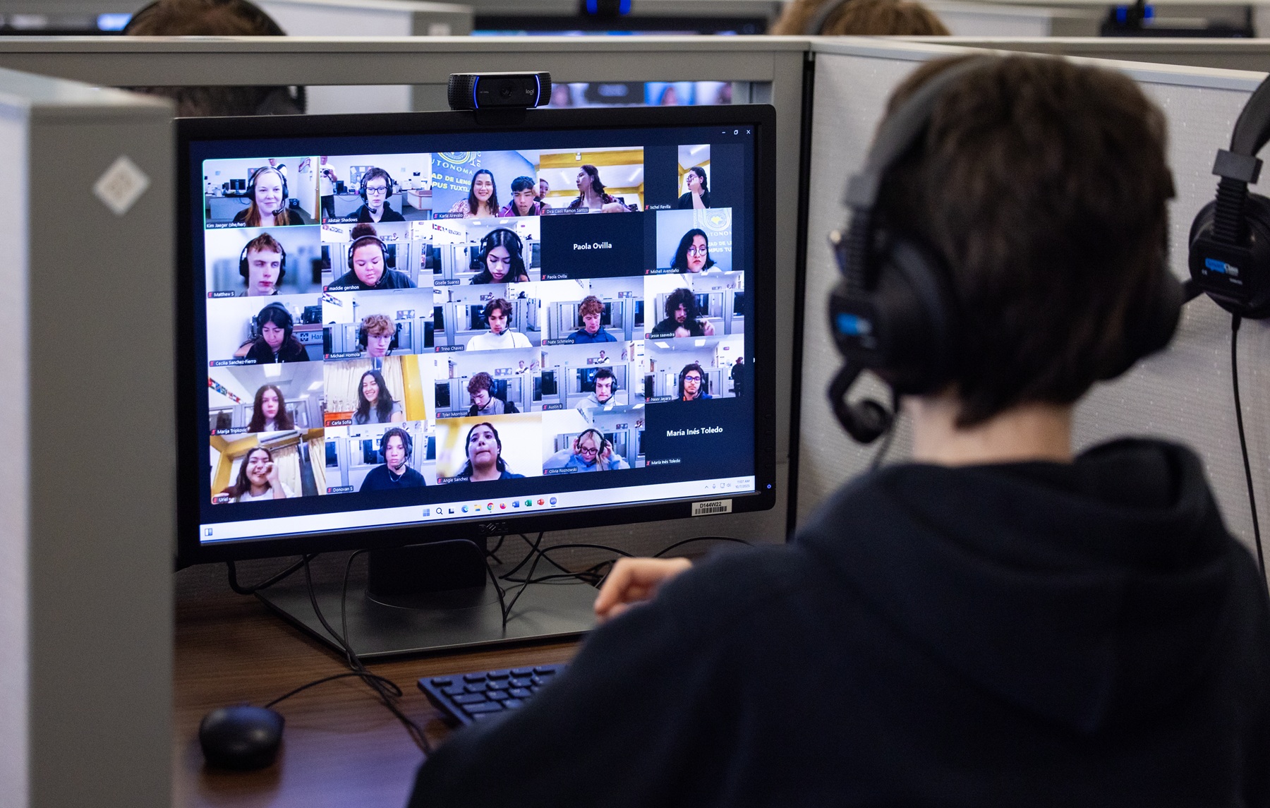 A Harper student looks at a computer screen showing other students from his class and from a class in Mexico.