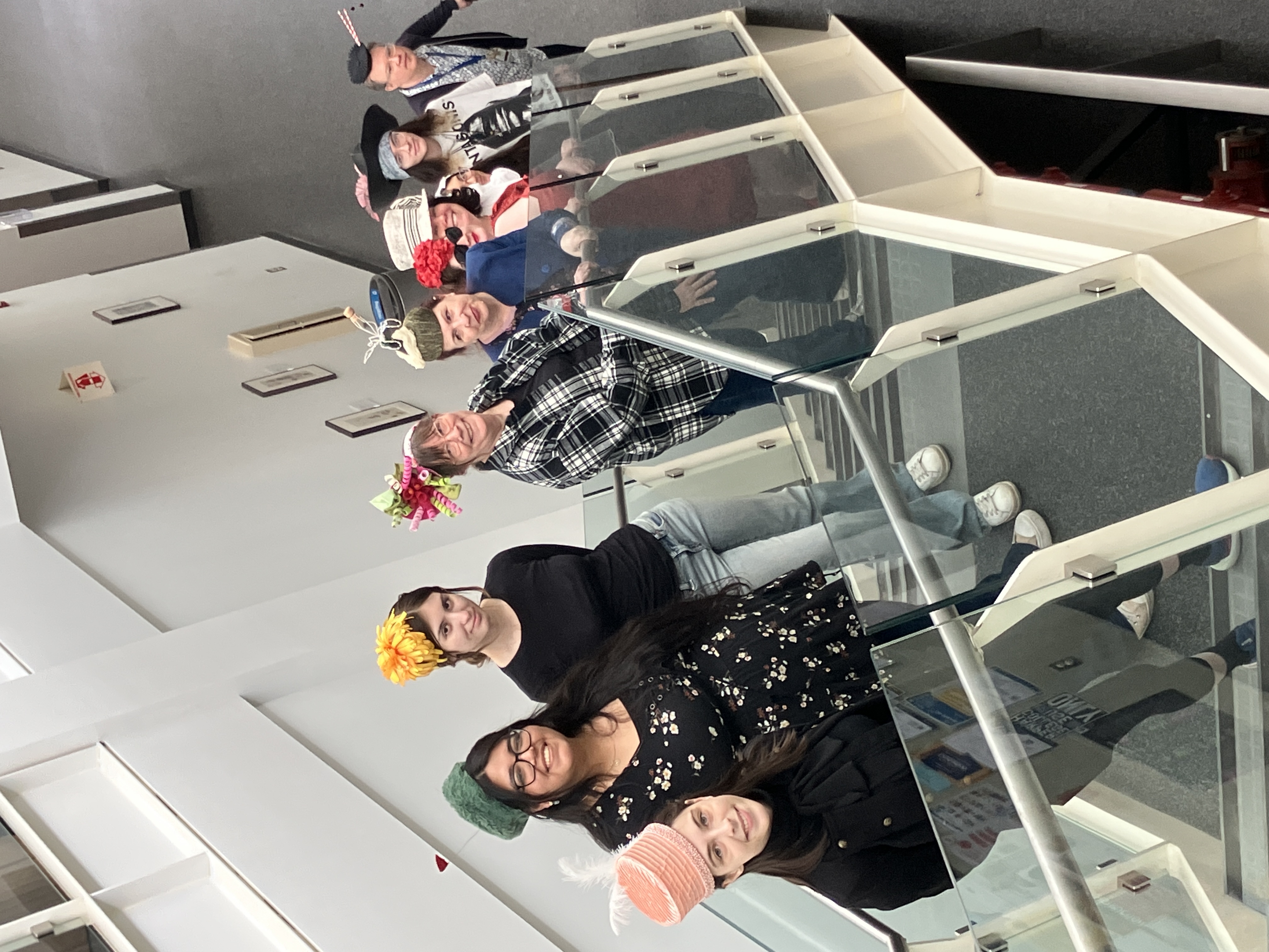 Students standing on a staircase wearing the hats they handmade.