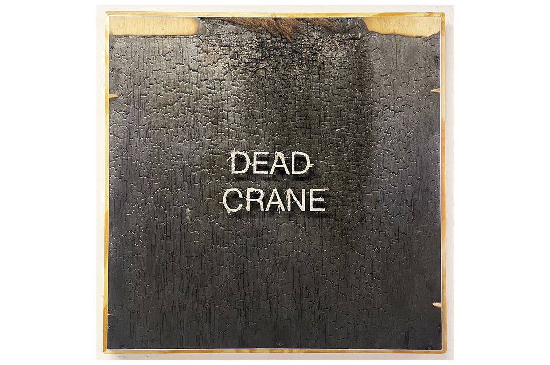 leather stretched over a board with the words 'dead crane' in metal letters