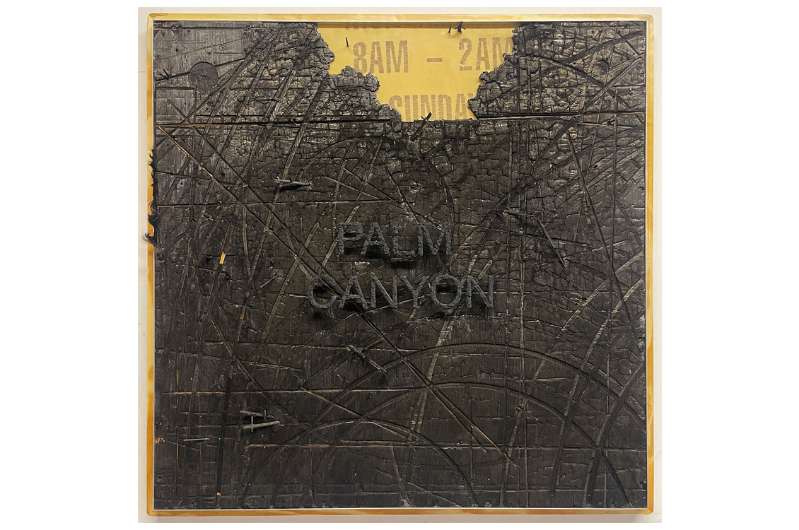 ripped piece of distressed leather stretched across a board with the words 'palm canyon' in dark letters