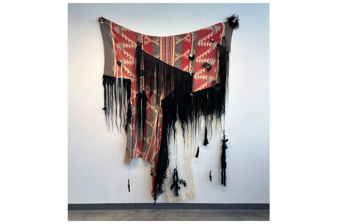 a fiber arts piece woven with native american patterns in red, gray, and black