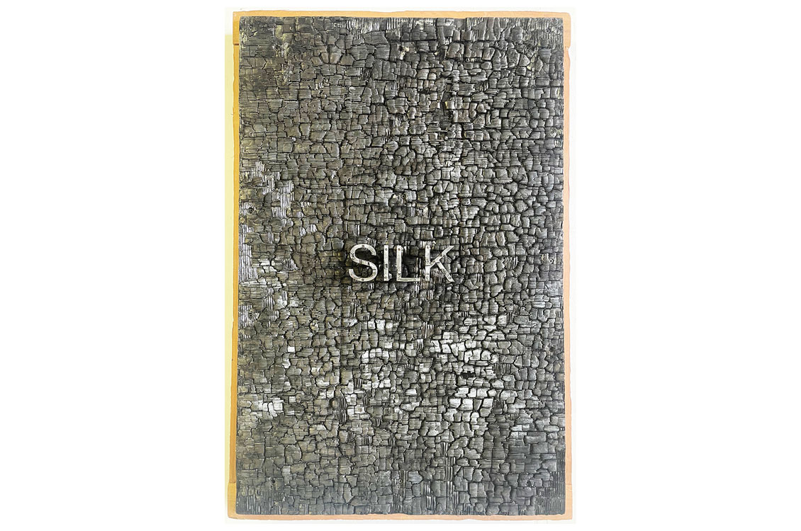 rough,flat piece of wood with the word 'silk' written on it