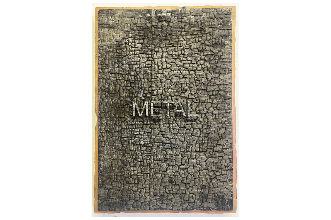 a rough, flat cut of wood with the word 'metal' written on it