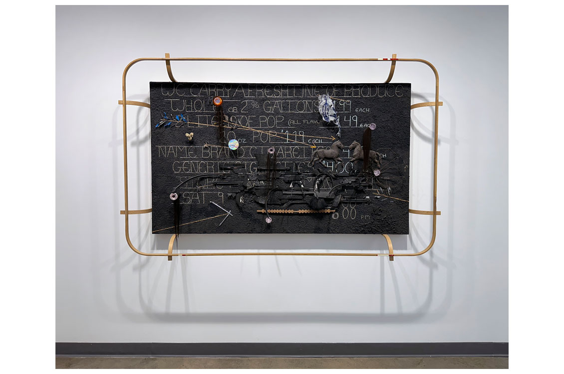 abstract metal sculpture with a chalkboard-like surface on the center that has various words written on it