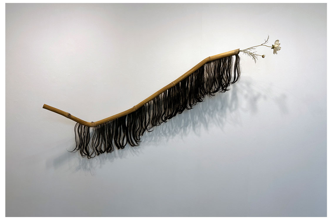 abstract art of a stick with flowers and black fringe