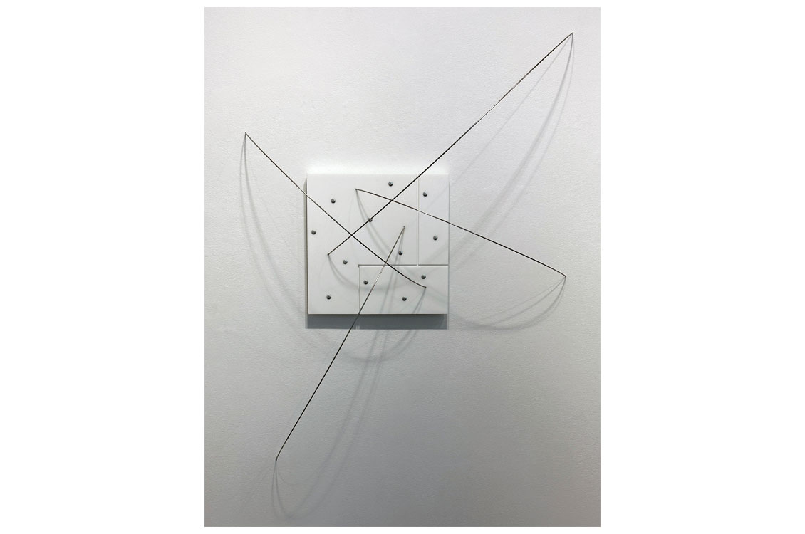 abstract wall sculpture with metal wires attached to a white square
