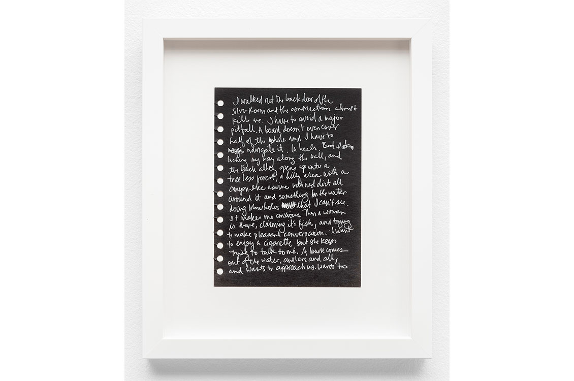 A poem hand-written with white pen on a background of black paper