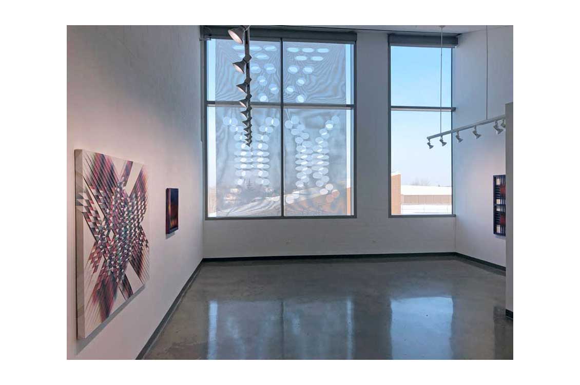 photo of gallery interior, with window installation center and canvases on the left