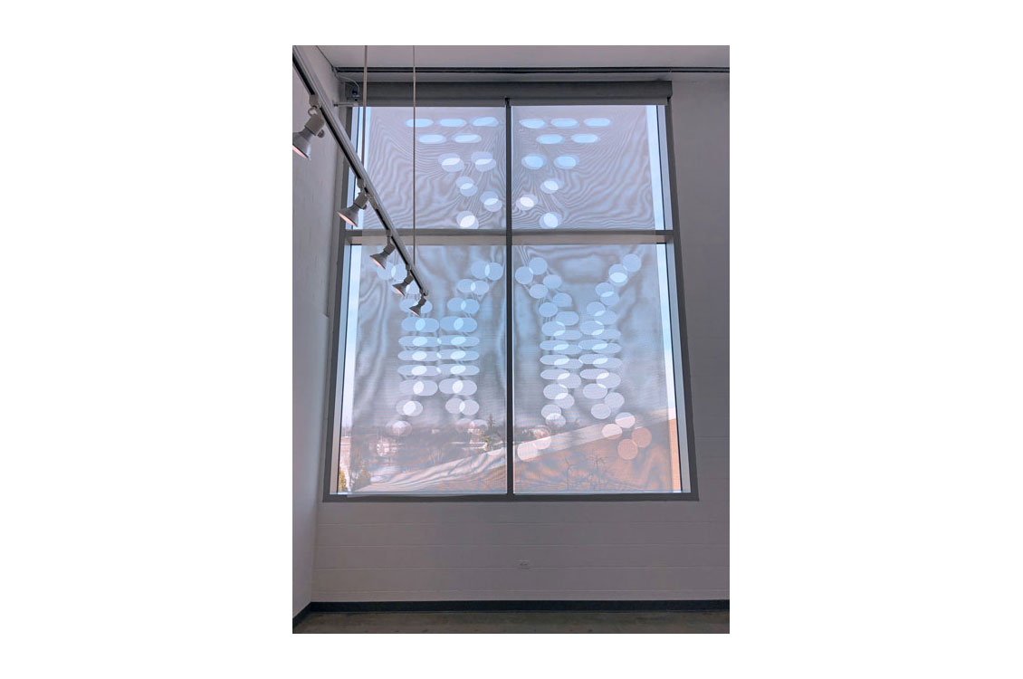 Mesh hung over window, the light refracts, creating shapes and colors