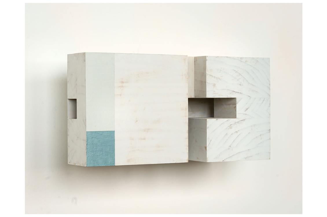 White block sculpture with pale blue square and carved recess.