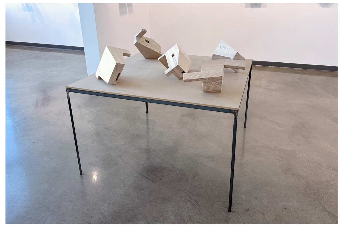 Table display of small unfinished wooden geometric sculptures.