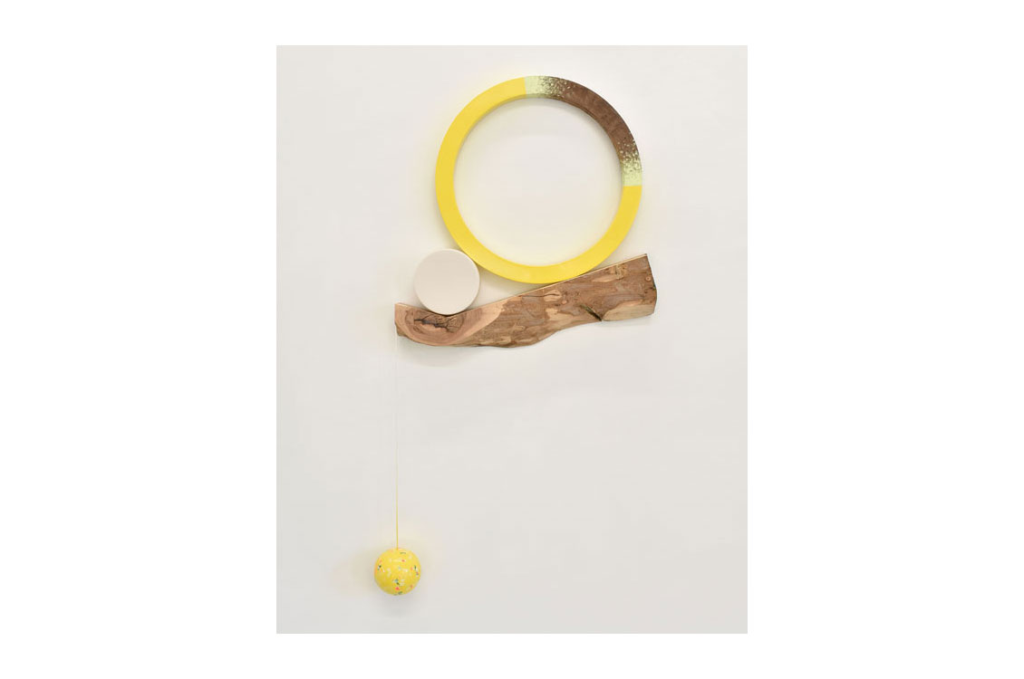 round yellow porcelain circle on a tree branch with a yellow porcelain ball hanging off of it
