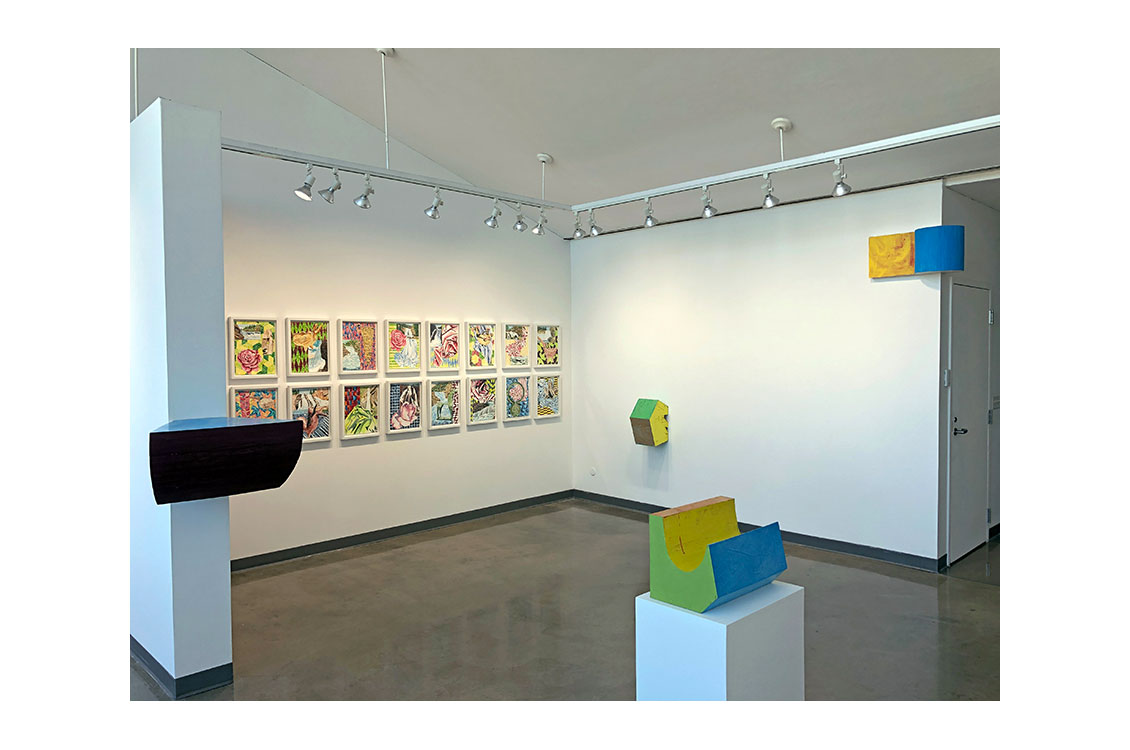 nterior view of gallery, with paintings on wall and wooded sculptures on display