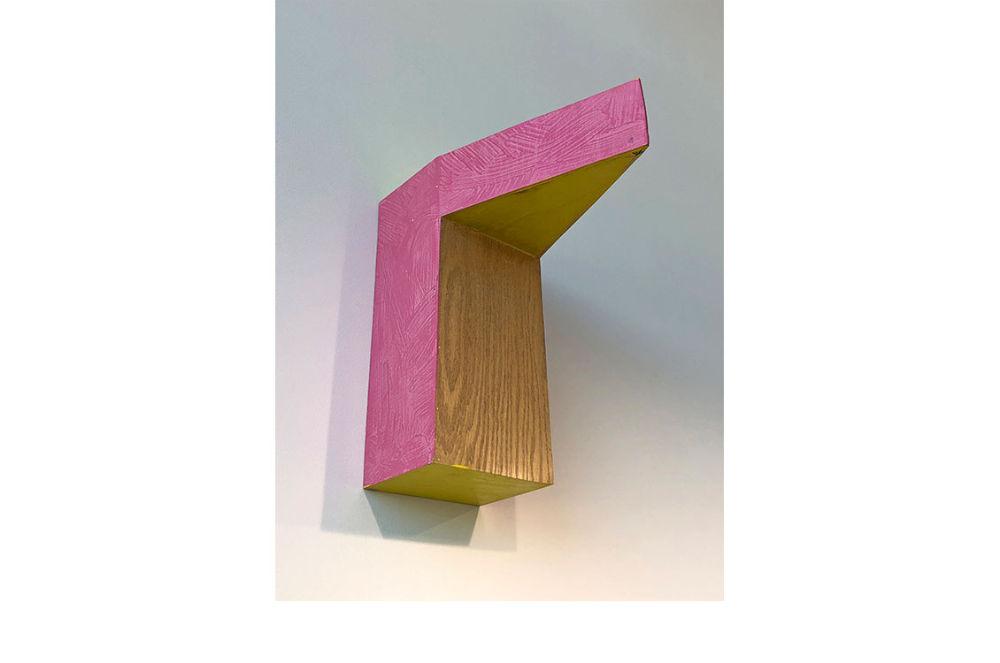 Wood sculputre hung on wall, two sides painted pink.